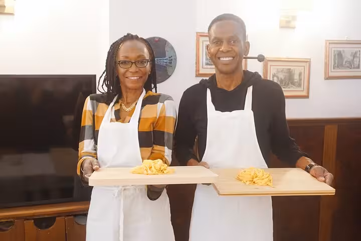 Smiling participants display their freshly made fettuccine during a pasta cooking class in Rome's Piazza Navona.