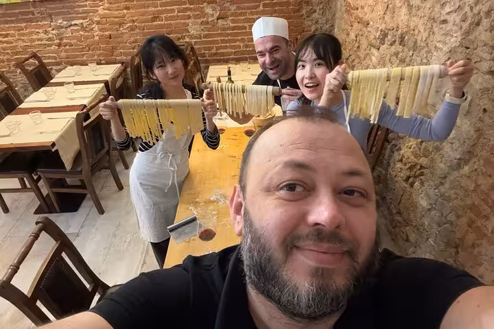 Participants proudly display freshly made pasta in a Florence cooking class with a certified chef.