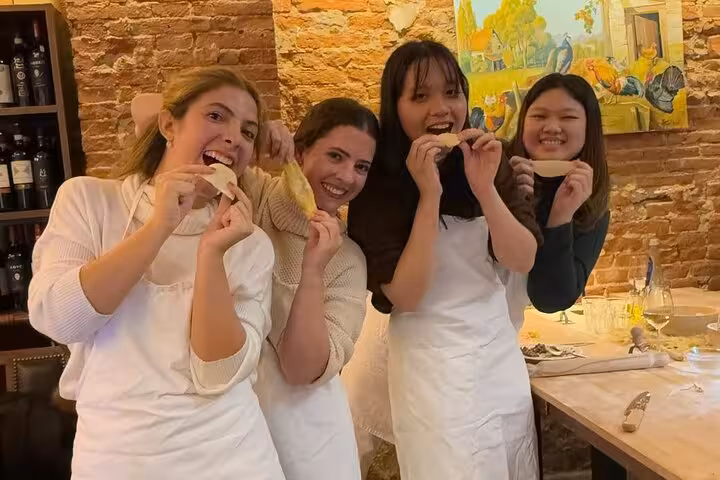 Group of friends enjoying a fun pasta-making experience in Florence, playfully tasting their creations.