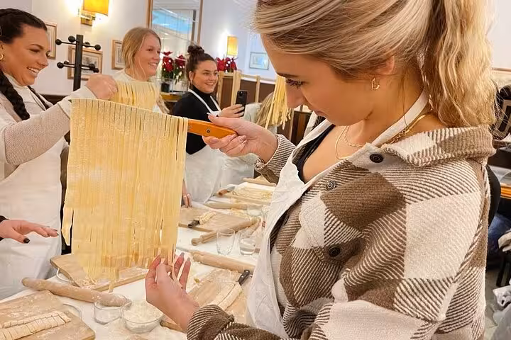 Participants in a Rome city center class skillfully craft fresh pasta sheets, showcasing hands-on Italian culinary traditions.