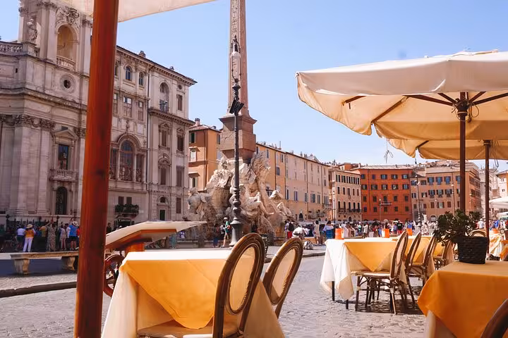 Outdoor dining setup in Piazza Navona, Rome, with tables overlooking historic architecture and vibrant city life.