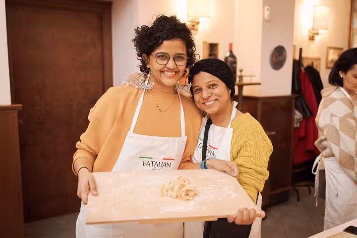 Two participants proudly display homemade pasta at a cooking class in Rome's Piazza Navona.