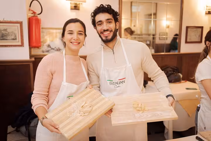 Smiling participants showcase freshly made pasta during a cooking class in Rome's Piazza Navona.