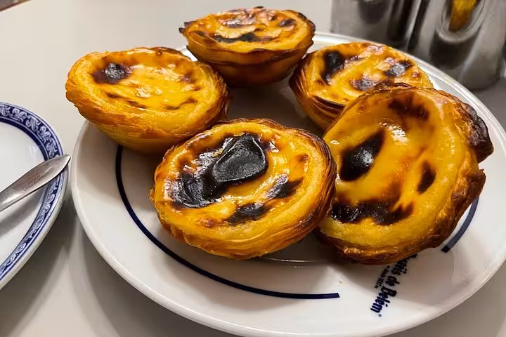 Close-up of warm pastéis de nata on a plate, iconic Lisbon treat on a 4-hour private tuk tuk tour