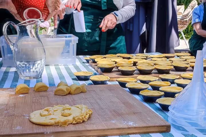 Hands-on baking class with dough preparation for Pastel de Nata on a striped tablecloth, ideal for food enthusiasts.