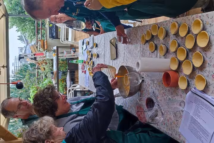Participants engaging in a Pastel de Nata baking session on a terrace, enhancing their culinary tour adventure.