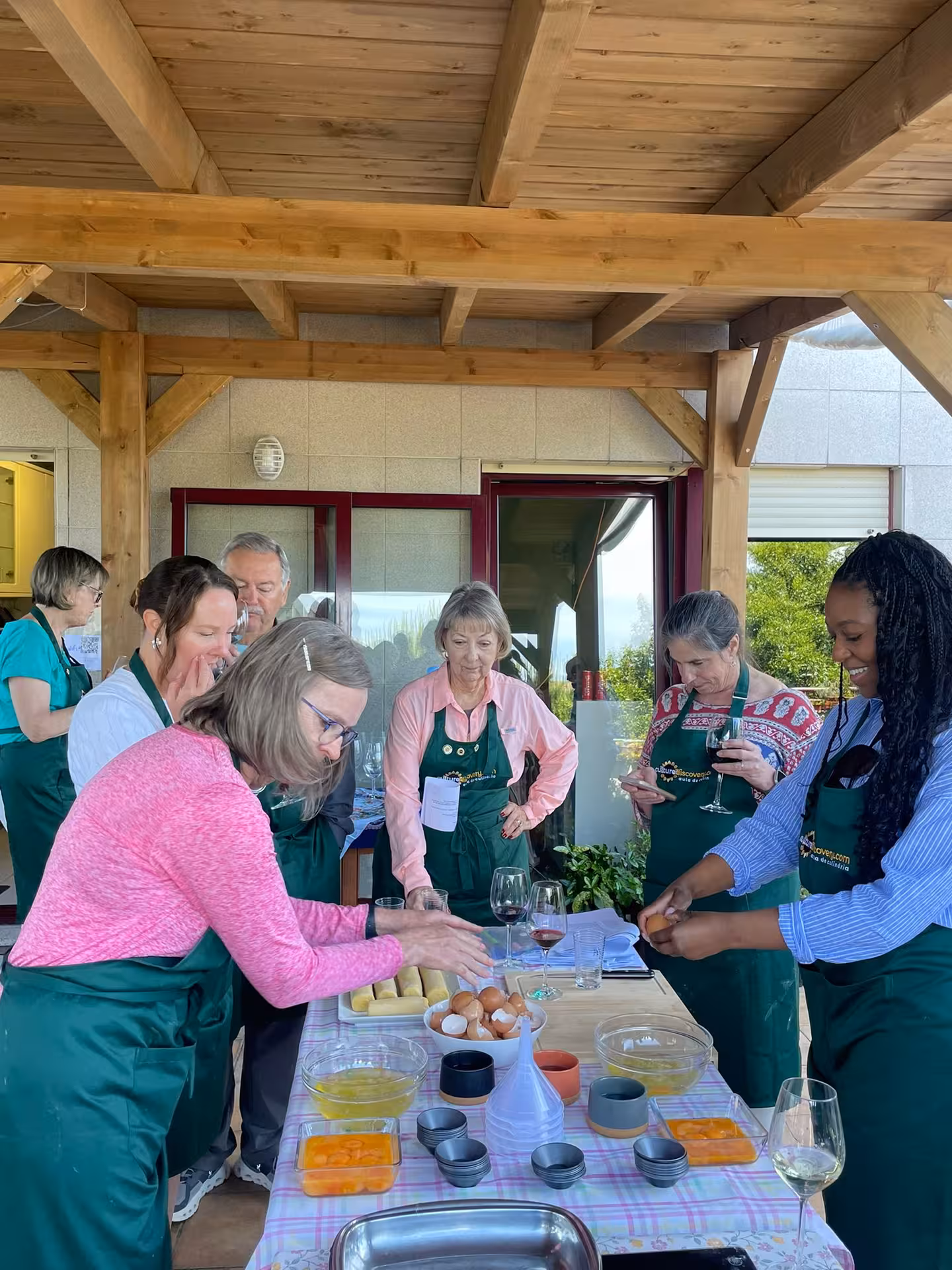 Group enjoying a hands-on pastel de nata cooking class on a terrace with Isabel and Jorge.