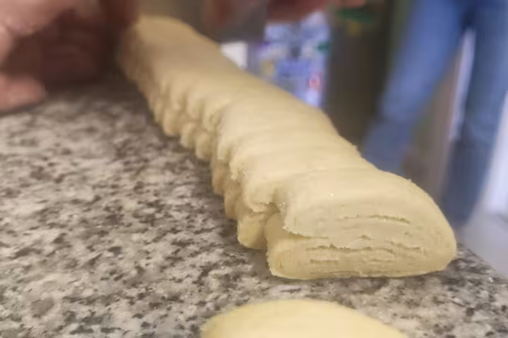 Close-up of freshly cut pastry dough lined up on a granite counter, ready for baking.