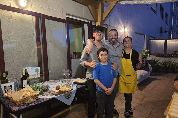 Family enjoying a cozy evening on a terrace with wine and snacks, perfect for a Pastel De Nata tour experience.