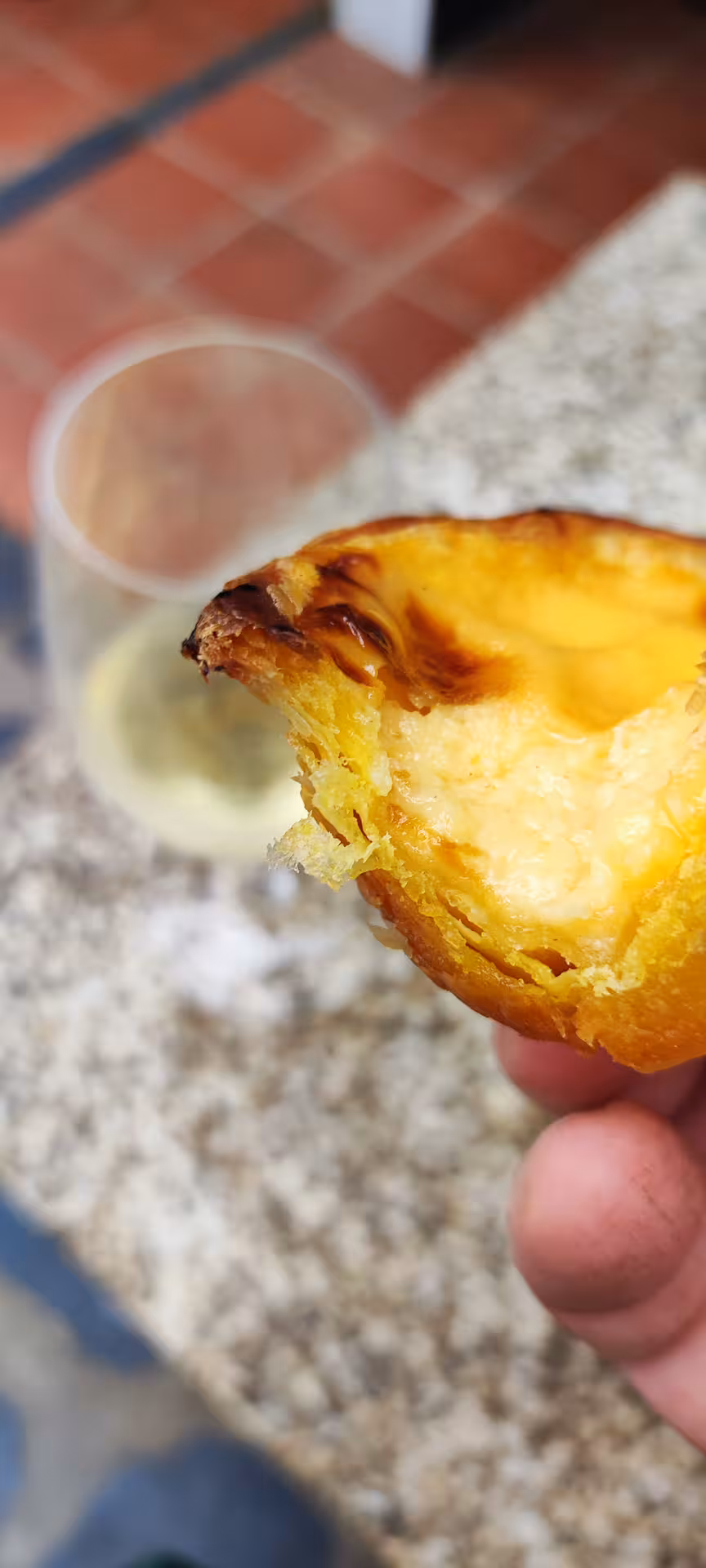 Close-up of a freshly baked pastel de nata with a glass of white wine at Porto cooking class.