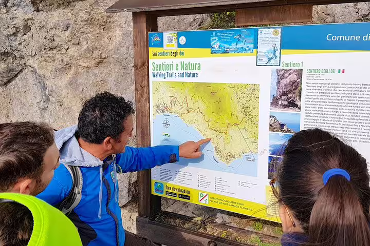 Guide explaining Path of the Gods hiking trail map to tourists at Sorrento starting point.