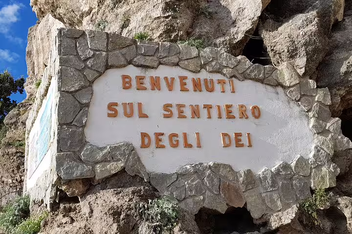 Stone sign reading 'Benvenuti sul Sentiero degli Dei' at the Path of the Gods trailhead near Sorrento, Italy.