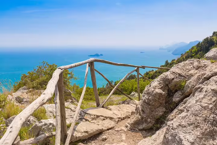 Scenic coastal view from Path of the Gods hiking trail near Sorrento with wooden railing and rocky landscape.