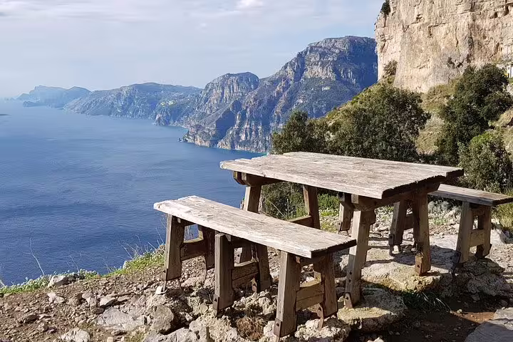 Scenic picnic spot with wooden benches overlooking the Amalfi Coast on the Path of the Gods near Sorrento.