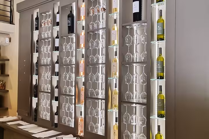 Backlit wine wall with bottles and stemware at Pce’s Vineyard, setting for sommelier course wine tasting