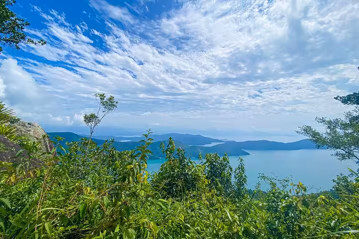 Breathtaking panoramic view of lush greenery and shimmering blue waters from Peak Sugar Bread summit adventure.