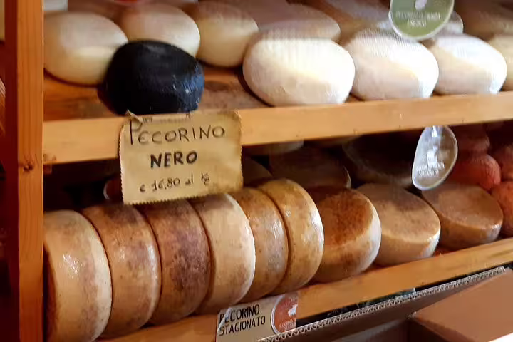 Artisanal pecorino wheels in a Tuscan shop, pairing perfectly with Brunello and Vino Nobile wines on a private tour