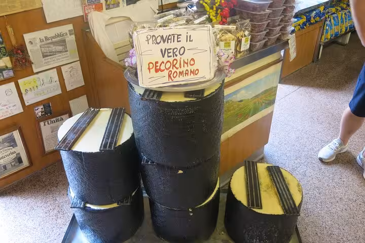 Display of authentic Pecorino Romano cheese wheels in a traditional Roman shop on a private vegetarian food tour.