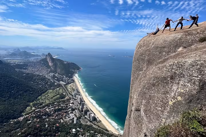 Thrill-seekers atop Pedra da Gávea, overlooking Rio's stunning coastline and lush landscapes.