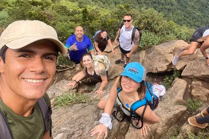 Excited hikers on a rocky trail at Pedra da Gávea, enjoying a challenging adventure with breathtaking views of Rio.