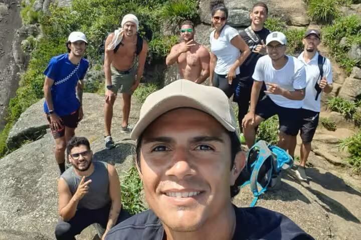 Group of hikers smiling on Pedra da Gávea's summit, capturing their achievement in Rio's stunning natural surroundings.