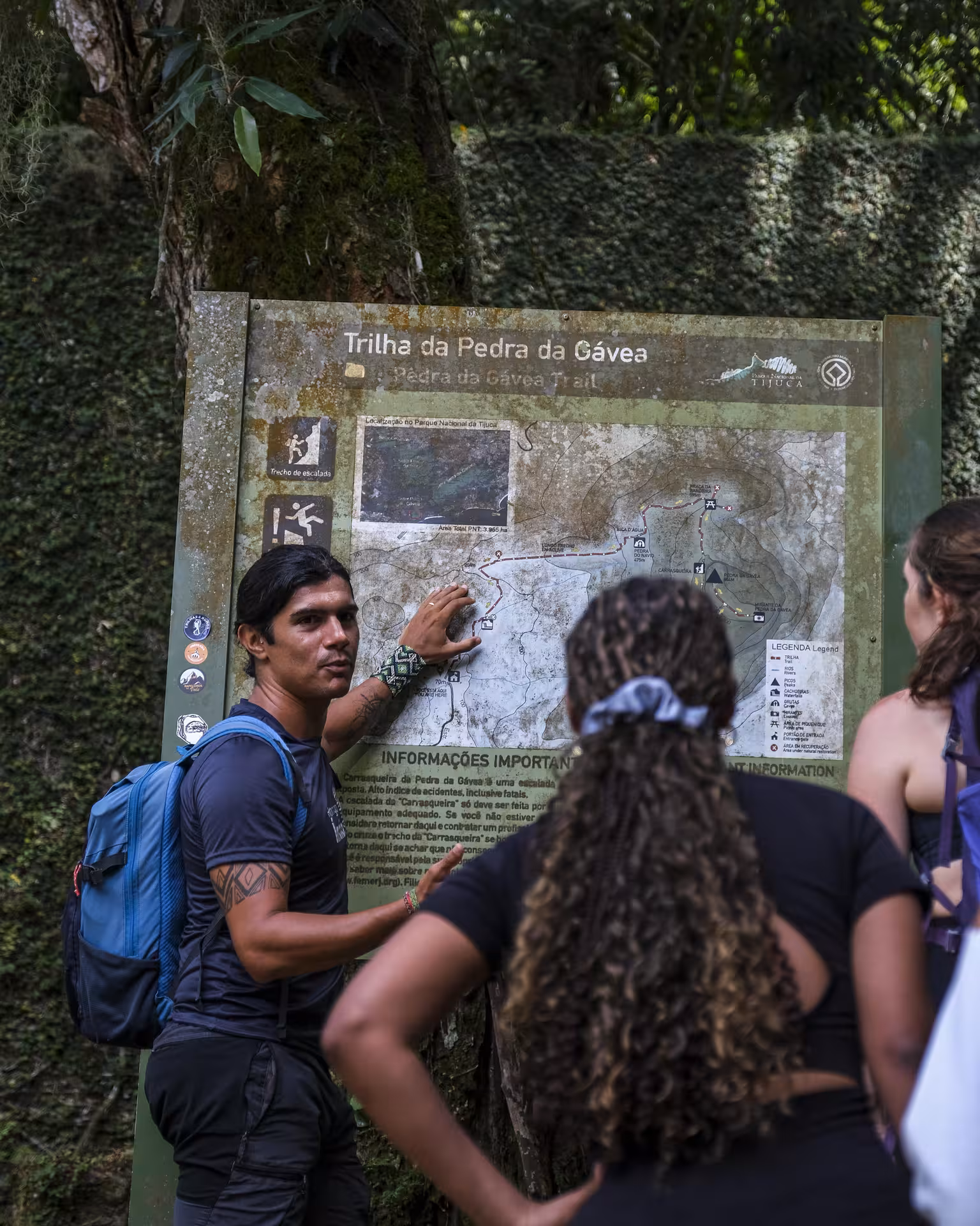 Guide explaining the Pedra da Gavea trail map to hikers, preparing for an exciting trek in Rio de Janeiro's landscape.