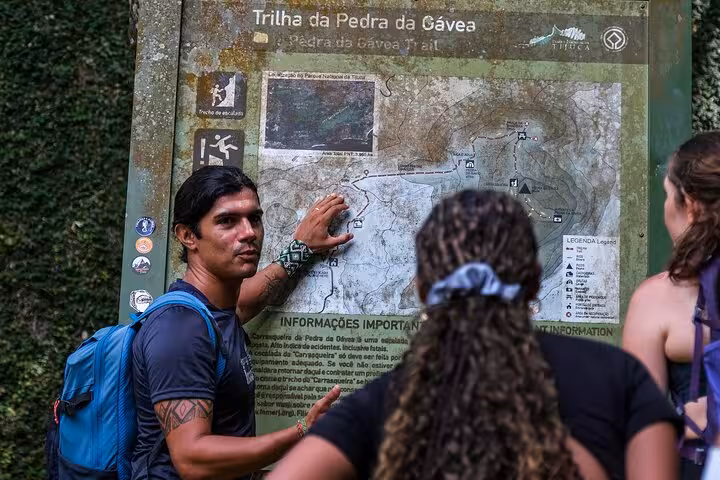 A guide explains the Pedra da Gávea trail map to hikers, preparing for an adventurous Rio experience.