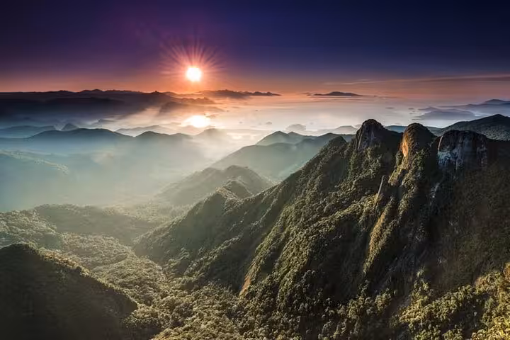 Breathtaking sunrise view over lush green mountains from Pedra da Macela, creating a serene and majestic landscape.