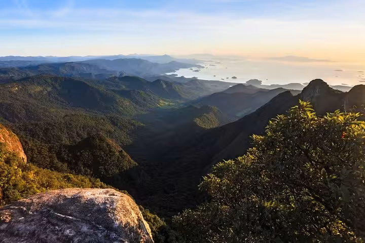 Stunning sunrise view from Pedra da Macela showcasing lush valleys and distant ocean vistas, perfect for Paraty tours.