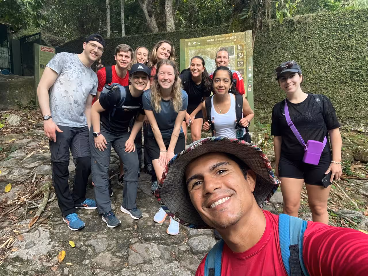 Happy hikers pose at the start of the Pedra da Gavea trail, ready for an adventure in Rio de Janeiro's lush forest.