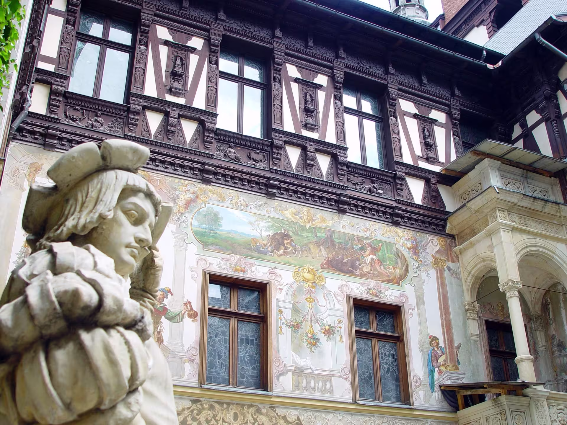 Detailed exterior view of Peles Castle showcasing ornate frescoes and sculptures, perfect for cultural tours in Romania.
