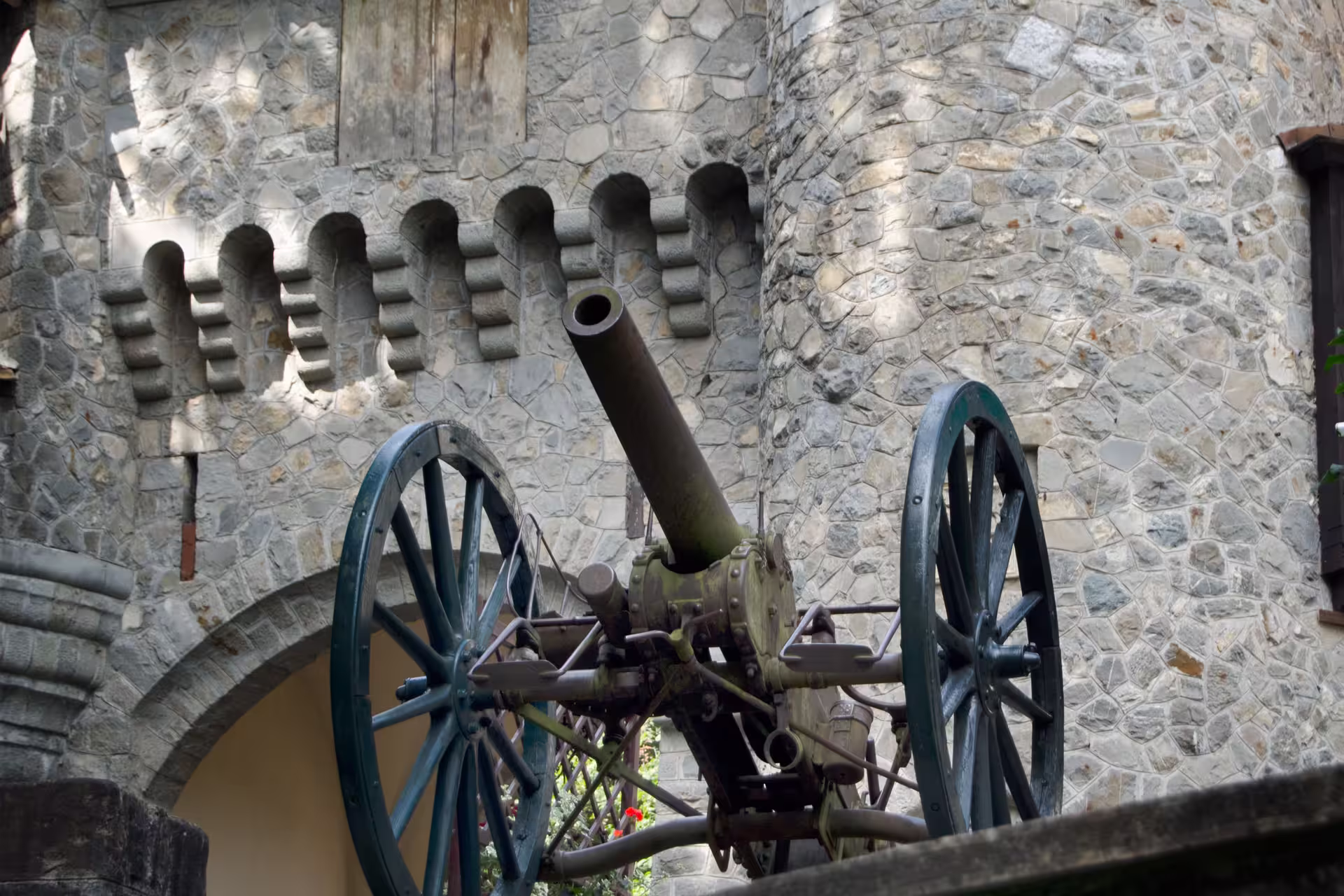 Historic cannon displayed against the stone architecture of Peles Castle, ideal for history enthusiasts visiting Romania.