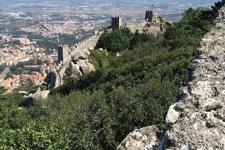 Stunning view of the ancient Moorish Castle walls overlooking lush greenery and Sintra town on a full-day tour to Pena Palace.