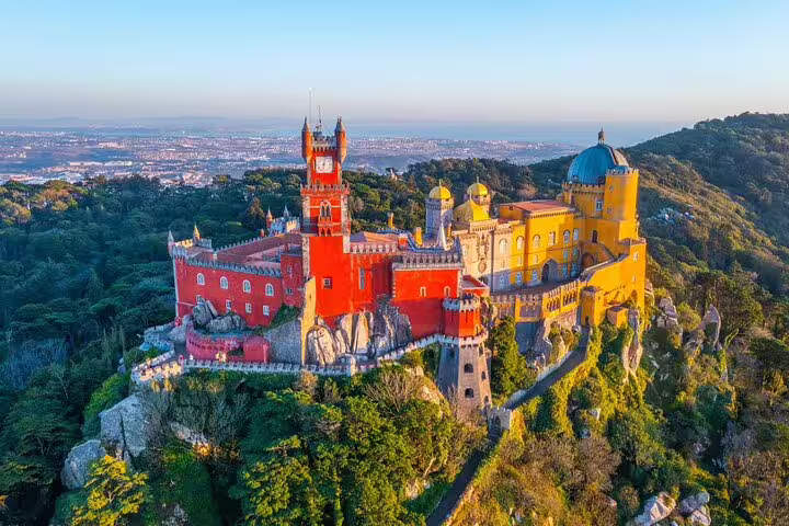 Aerial view of the colorful Pena Palace in Sintra, surrounded by lush greenery, a highlight of Lisbon guided tours.