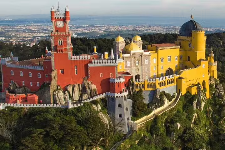 Stunning aerial view of the vibrant Pena Palace in Sintra, highlighting its colorful architecture and scenic surroundings.