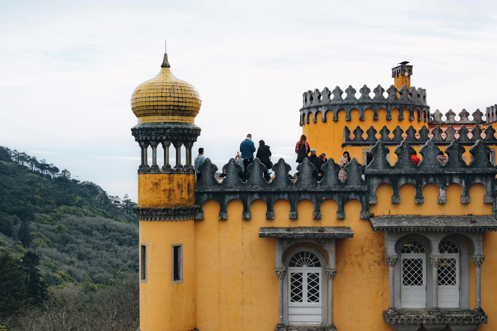 Visitors explore the vibrant architecture of Pena Palace in Sintra, surrounded by lush landscapes and historical charm.