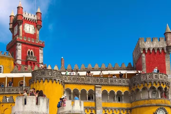 Colorful turrets and intricate architecture of Pena Palace under a clear blue sky, highlighting the Sintra and Cascais tour experience.