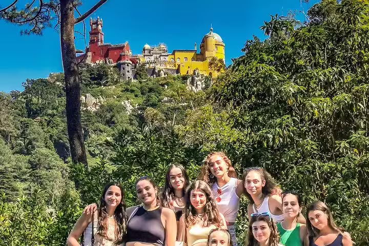 Group of tourists enjoying scenic views of the vibrant Pena Palace in Sintra during a half-day tour from Lisbon.