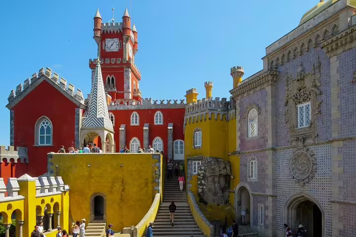 Vibrant Pena Palace in Sintra with colorful architecture and tourists, featured in our Lisbon day tour to Cascais and Sintra.