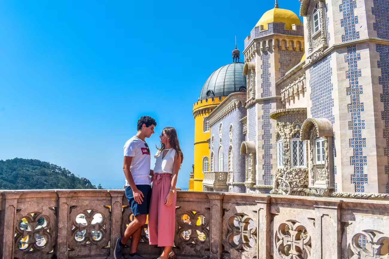 Couple enjoying the scenic balcony of Pena Palace in Sintra, highlighting its vibrant architecture and romantic allure.