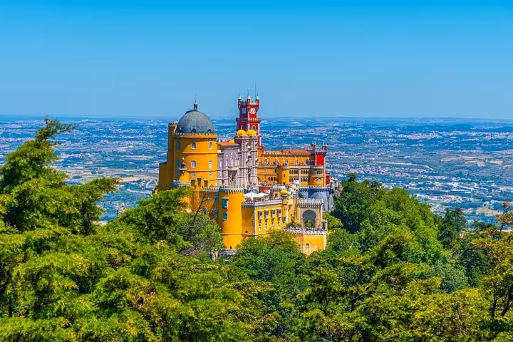Discover the enchanting view of Pena Palace surrounded by lush forests on the Sintra day tour from Lisbon.