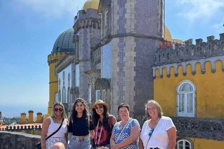 Group enjoying the vibrant architecture of Pena Palace during a full-day tour to Sintra, Cabo da Roca, and Cascais.