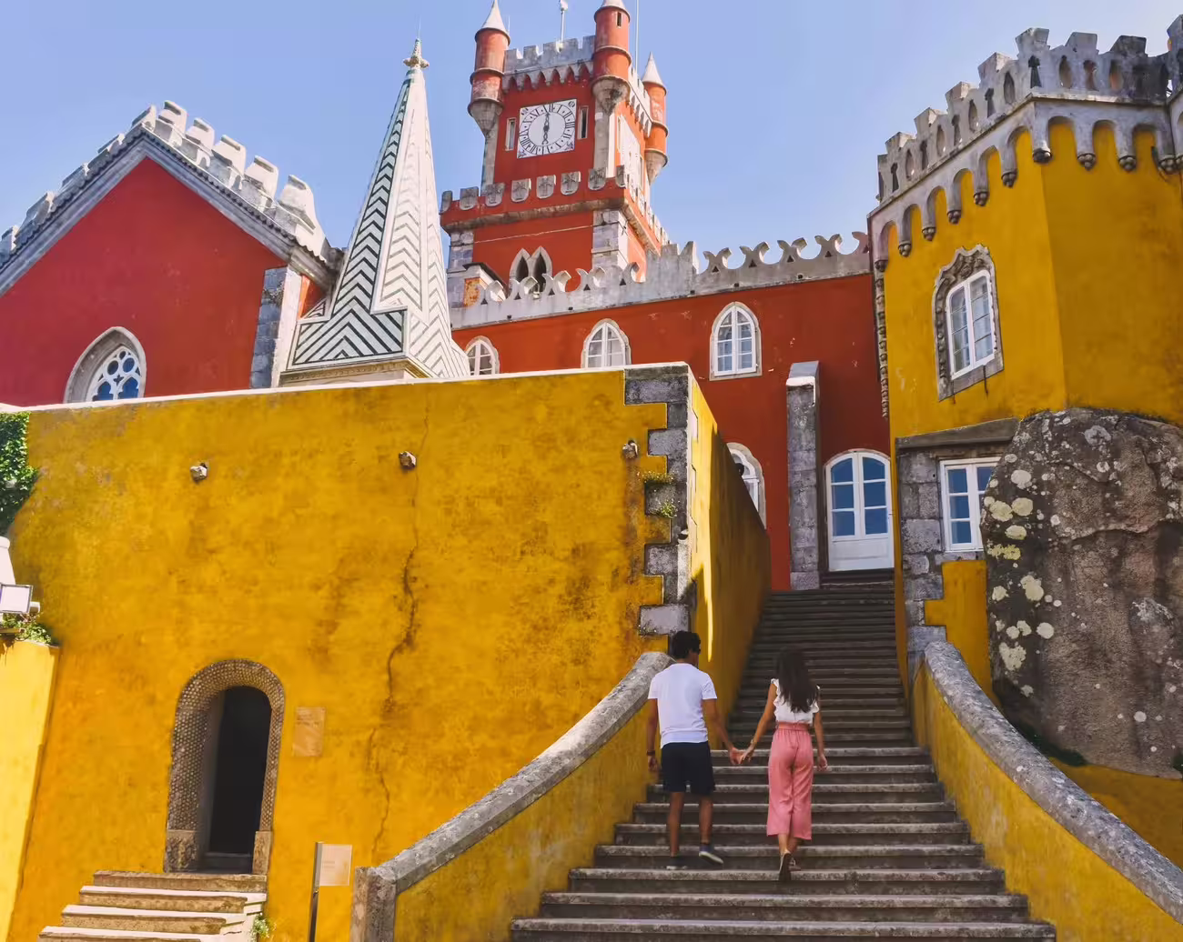 A couple ascends the grand staircase of Pena Palace, a must-see on the guided tour of Sintra and Cabo da Roca.