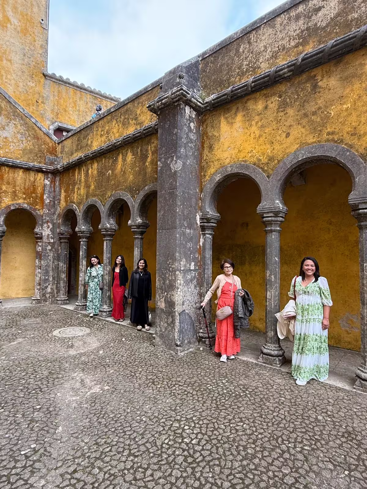 Tourists exploring the historic arches and vibrant architecture of Pena Palace in Sintra.