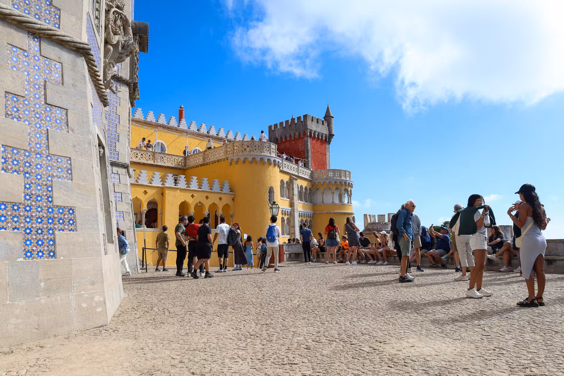 Visitors explore the vibrant architecture of Pena Palace on a sunny day during the Sintra day tour from Lisbon.