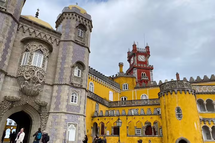 Pena Palace in Sintra with vibrant yellow and red towers, a highlight of the Sintra, Cabo da Roca, Cascais day trip from Lisbon.