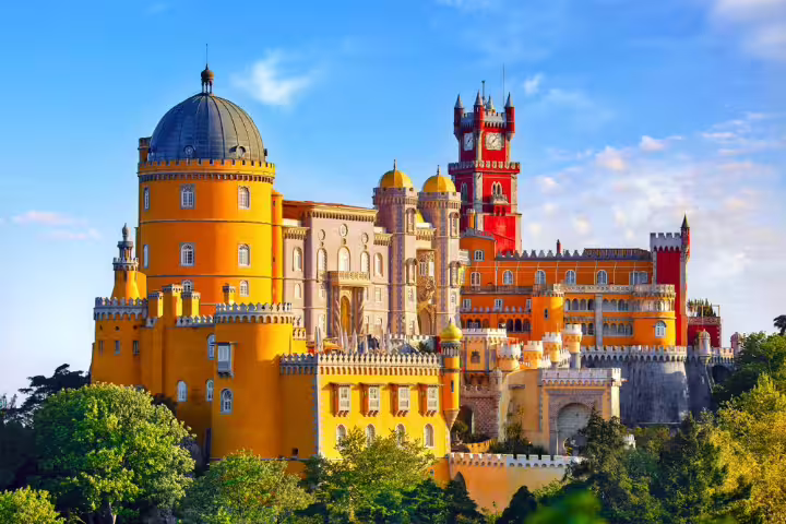 Vibrant view of the colorful Pena Palace in Sintra, showcasing its iconic architecture against a clear blue sky, ideal for Lisbon tours.