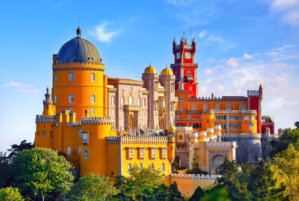 Vibrant view of the Pena Palace in Sintra, showcasing its colorful architecture against a clear blue sky, perfect for Lisbon tours.