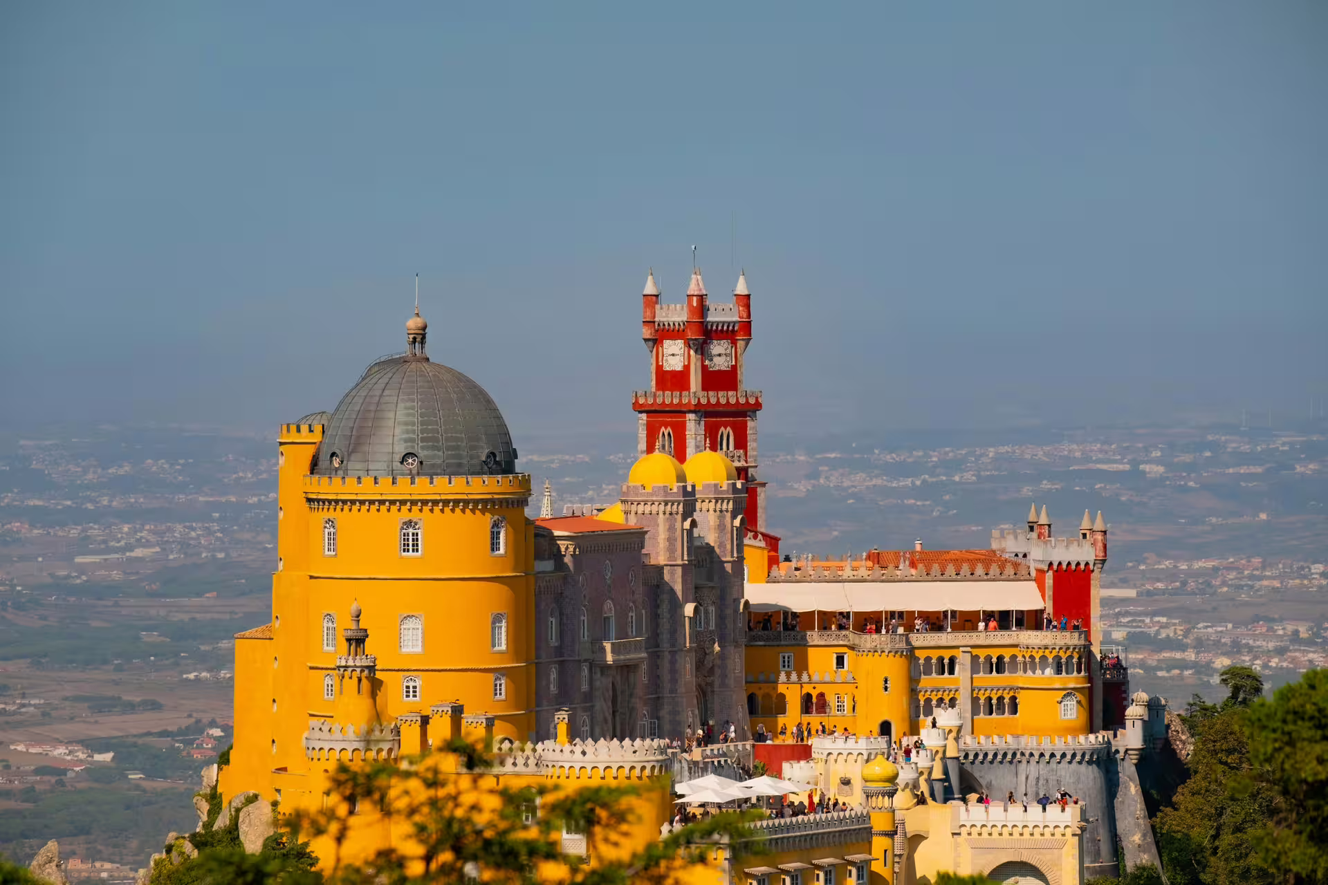 Vibrant view of Pena Palace in Sintra, showcasing colorful architecture against a scenic landscape, ideal for Lisbon tours.