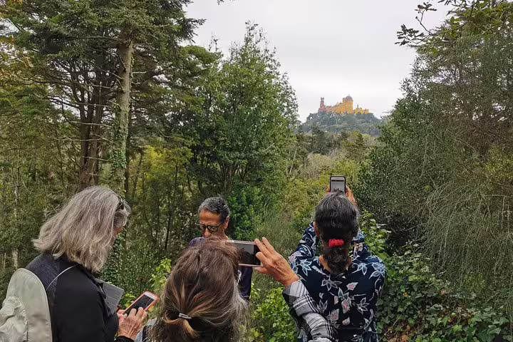 Tourists capturing the scenic view of Pena Palace in Sintra during a private Lisbon, Roca, and Cascais two-day tour.